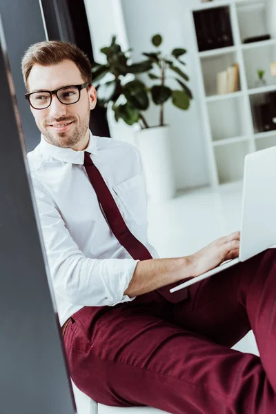 英俊微笑的商人在眼镜使用笔记本电脑 — 免费的图库照片