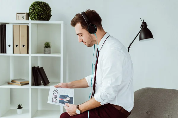Όμορφος Επιχειρηματίας Ακούγοντας Μουσική Στα Ακουστικά Και Διαβάζει Εφημερίδα — Φωτογραφία Αρχείου