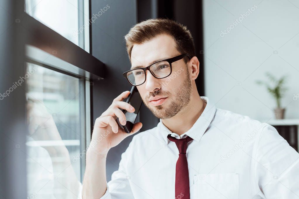 handsome stylish businessman talking on smartphone in office