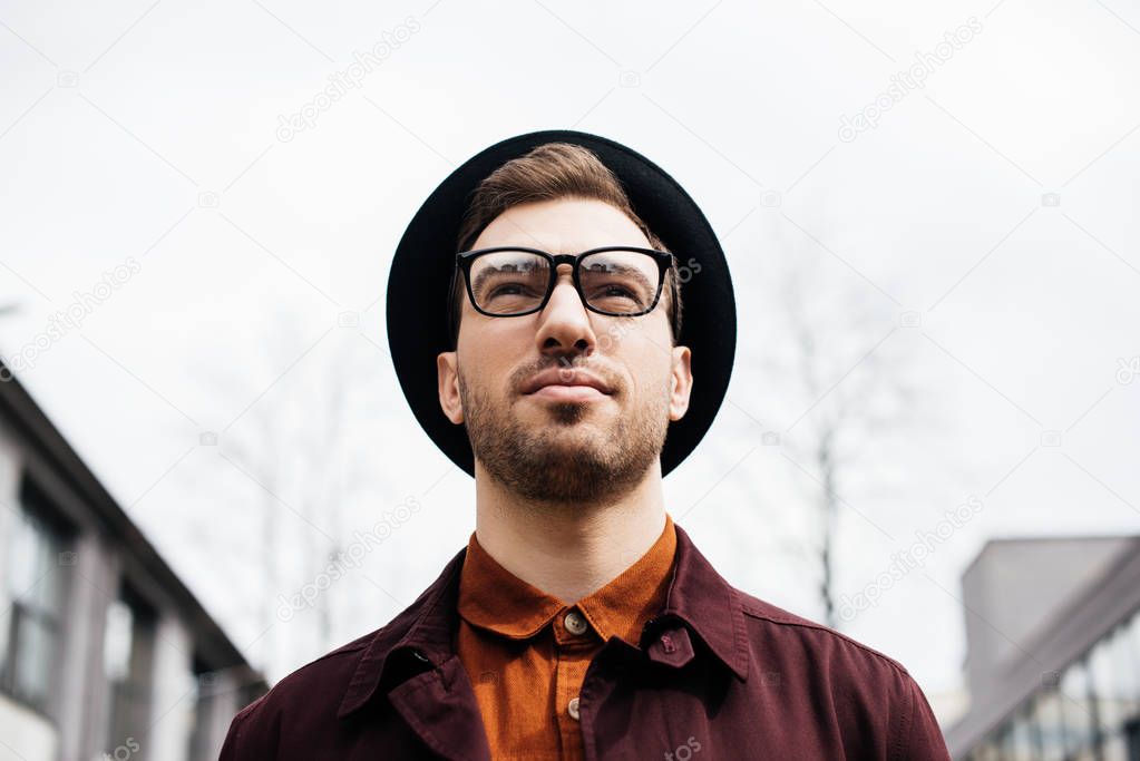 bottom view of handsome fashionable man in eyeglasses and hat