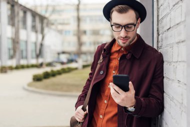 smartphone kullanarak bir çanta trendy kıyafetler içinde şık yakışıklı