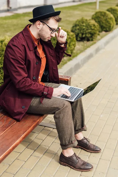 Joven Guapo Usando Ordenador Portátil Mientras Está Sentado Banco — Foto de stock gratuita