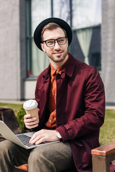 Knappe Modieuze Man Met Koffie Gaan Met Behulp Van Laptop — Gratis stockfoto