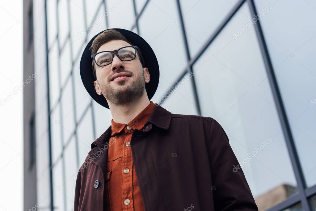 bottom view of handsome stylish man posing in glasses and trendy hat  