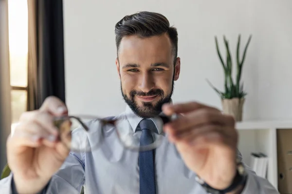 Empresário segurando óculos — Fotografia de Stock