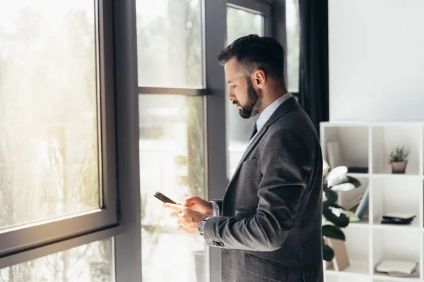 Geschäftsmann tippt im Büro auf Smartphone — Stockfoto