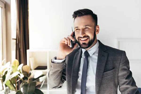 Uomo d'affari sorridente che parla su smartphone in ufficio — Foto stock