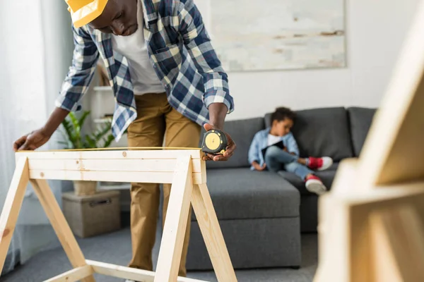 Man measuring wooden plank with tape — Stock Photo
