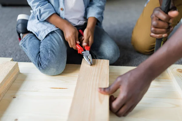 Father and son pulling screw out of plank — Stock Photo