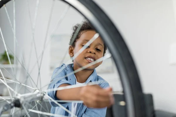 Glücklicher afrikanischer Junge repariert Fahrrad — Stockfoto