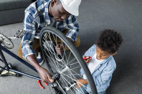 Афро батько і син ремонтують велосипед — стокове фото