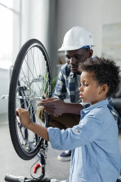 Afro padre e hijo reparando bicicleta - foto de stock