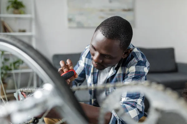 Afro man repairing bicycle at home — Stock Photo