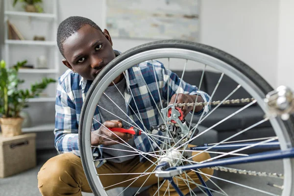Афро чоловік ремонтує велосипед вдома — стокове фото