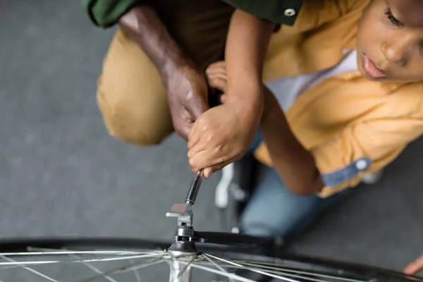 Афро отец и сын ремонтируют велосипед — стоковое фото