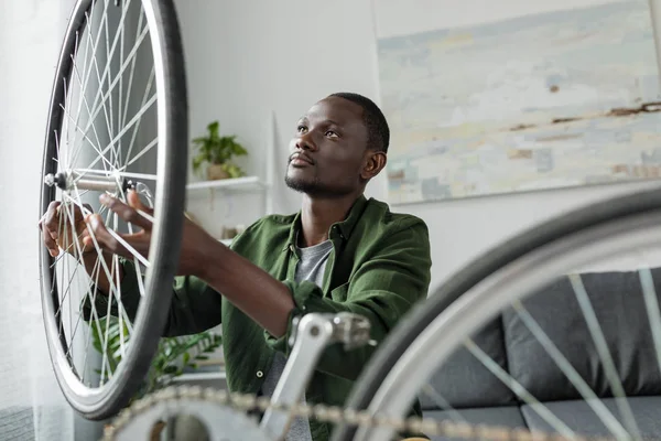 Afro homem reparação de bicicleta em casa — Fotografia de Stock