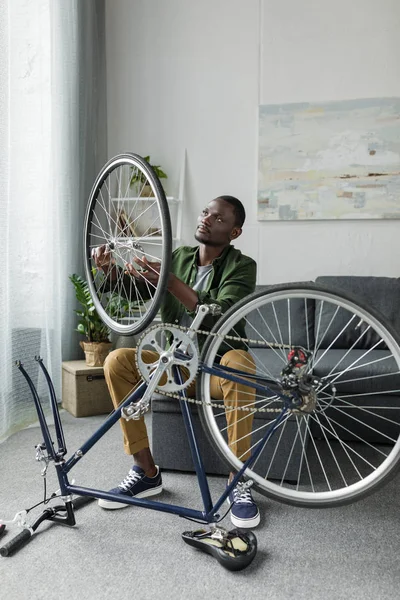 Afro homem reparação de bicicleta em casa — Fotografia de Stock