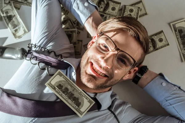 Молодой богатый бизнесмен лежит на долларовых купюрах — стоковое фото