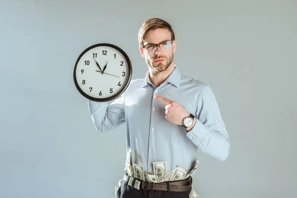 Young confident businessman pointing on clock isolated on grey — Stock Photo