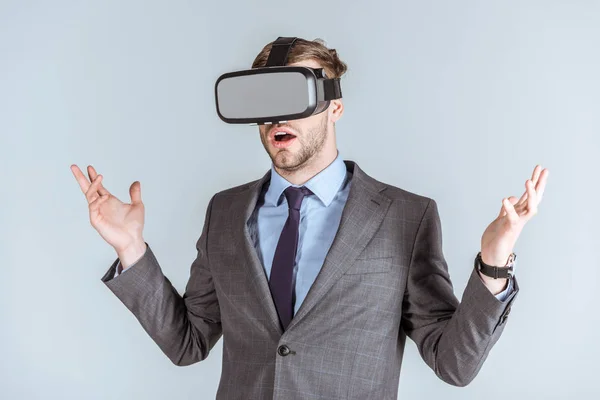 Joven hombre de negocios usando auriculares vr aislados en gris - foto de stock