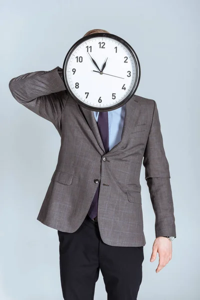 Businessman in suit holding clock over his face isolated on grey — Stock Photo