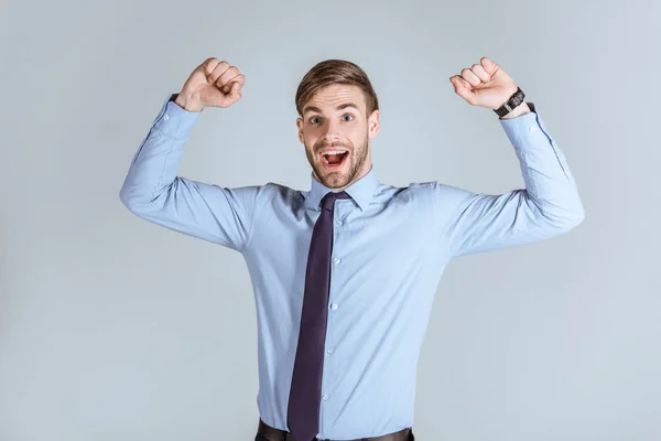 Молодий сильний бізнесмен піднімає руки вгору ізольовано на сірому — стокове фото