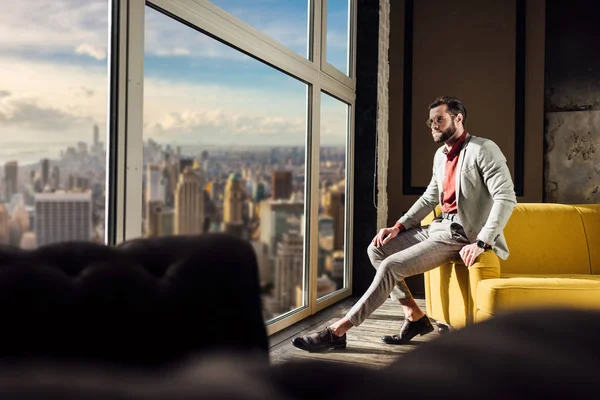Homme élégant à la mode en costume élégant posant à la fenêtre avec vue sur la ville — Photo de stock