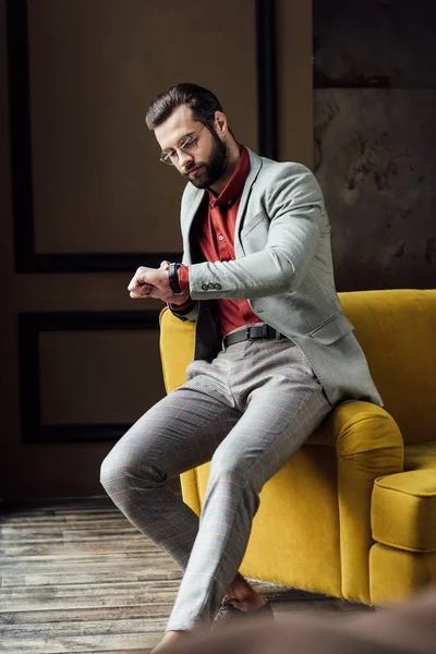 Красивий бородатий елегантний чоловік дивиться на годинник — стокове фото