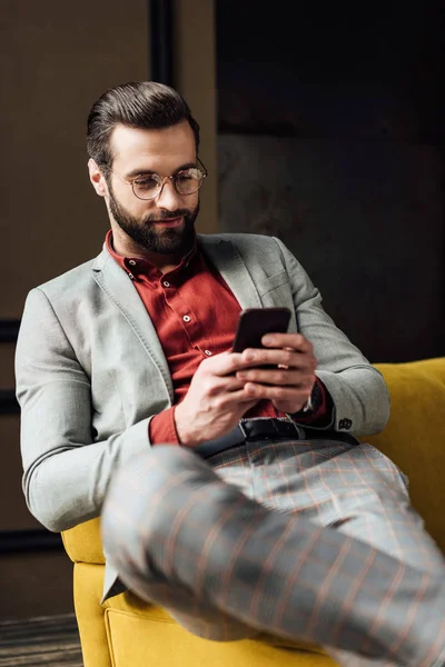 Homem elegante bonito em óculos usando smartphone — Fotografia de Stock