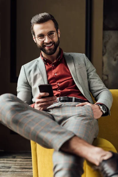 Bello uomo allegro in occhiali utilizzando smartphone — Foto stock