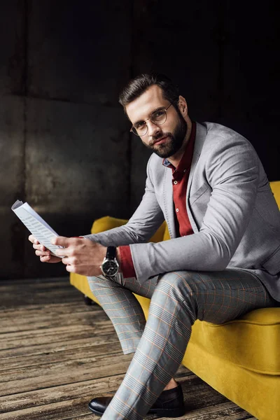 Schöner Geschäftsmann im Anzug, der Zeitung liest und auf der Couch sitzt — Stockfoto