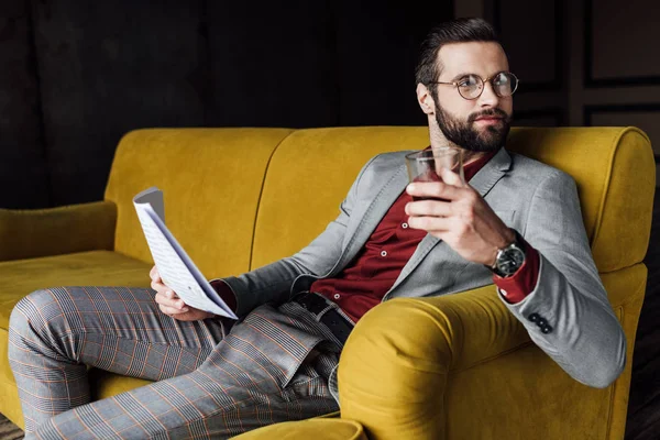 Uomo elegante che tiene giornale e vetro di cognac — Foto stock