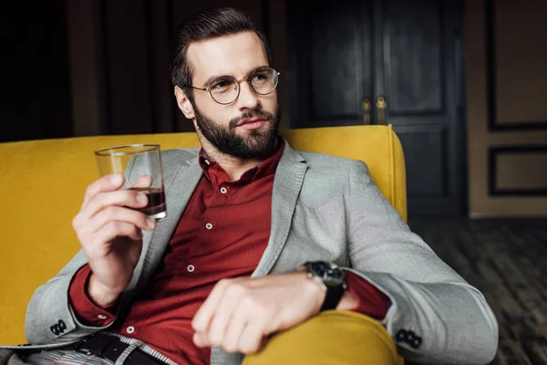 Stylish bearded man holding glass of whiskey — Stock Photo