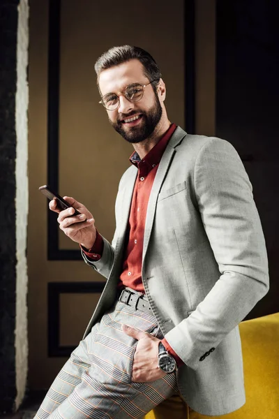 Cheerful fashionable handsome man using smartphone — Stock Photo