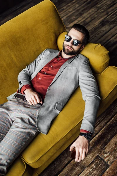 Overhead view of sleeping drunk man in sunglasses with glass of whiskey — Stock Photo