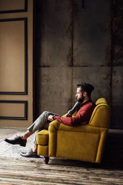 Homme élégant à la mode assis sur un canapé jaune — Photo de stock