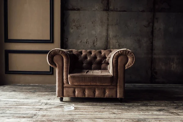 Luxurious brown armchair and ashtray on floor in loft interior — Stock Photo