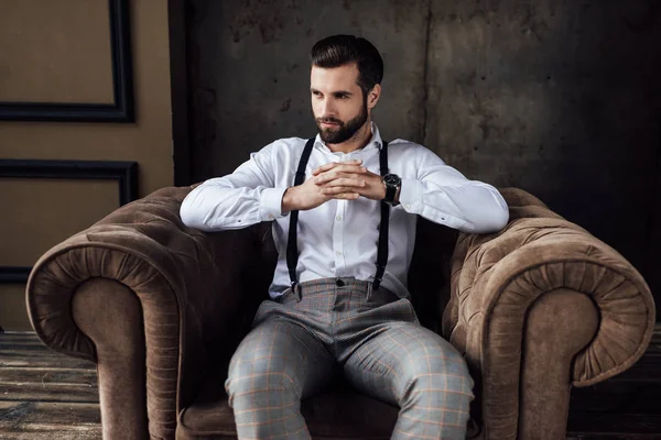 Homem elegante bonito pensando e sentado em poltrona — Fotografia de Stock