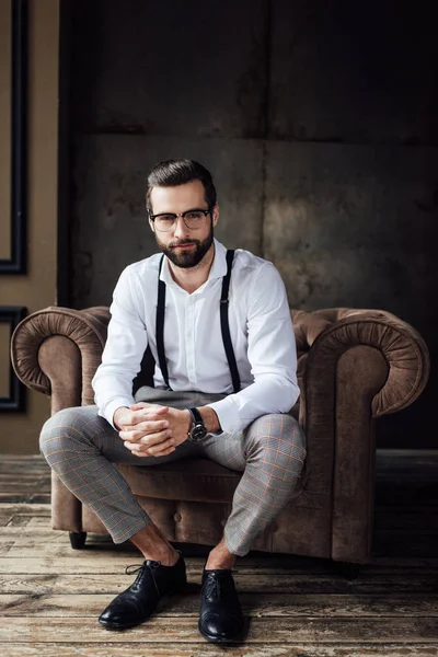 Modischer Mann mit Brille und Hosenträgern im Sessel — Stockfoto