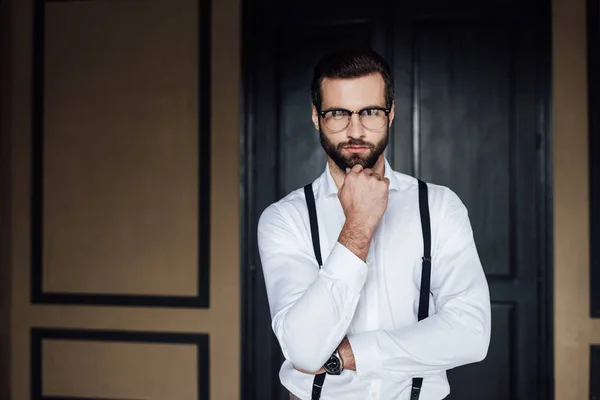 Вдумливий елегантний чоловік позує в білій сорочці і підтяжки — стокове фото
