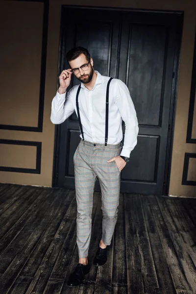 Homme élégant à la mode posant en chemise blanche et bretelles à l'intérieur loft — Photo de stock