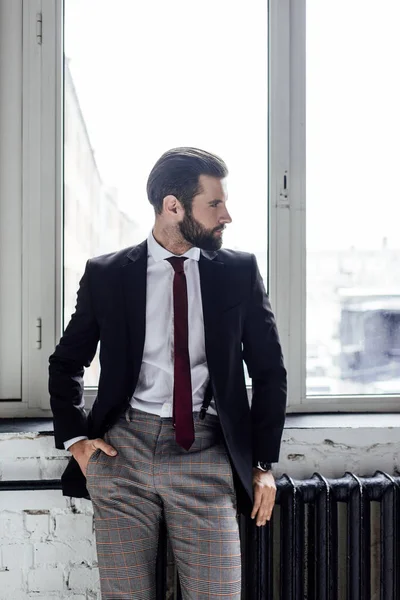 Guapo elegante hombre de negocios posando en traje en ventana - foto de stock