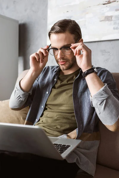 Handsome stylish man working with laptop on couch — Stock Photo