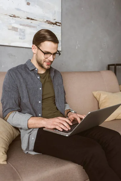 Heureux homme élégant travaillant avec ordinateur portable sur le canapé — Photo de stock