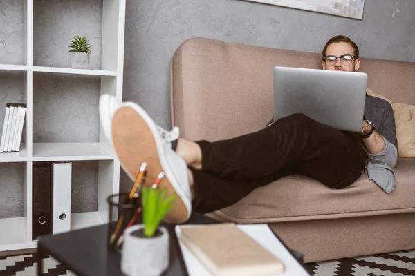 Stylische junge Freiberuflerin arbeitet mit Laptop auf der Couch — Stockfoto