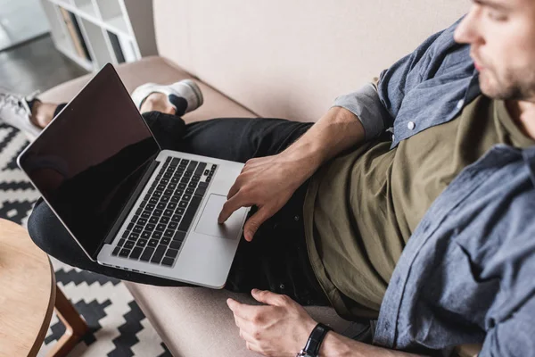 Nahaufnahme eines gutaussehenden Mannes, der mit Laptop auf der Couch arbeitet — Stockfoto