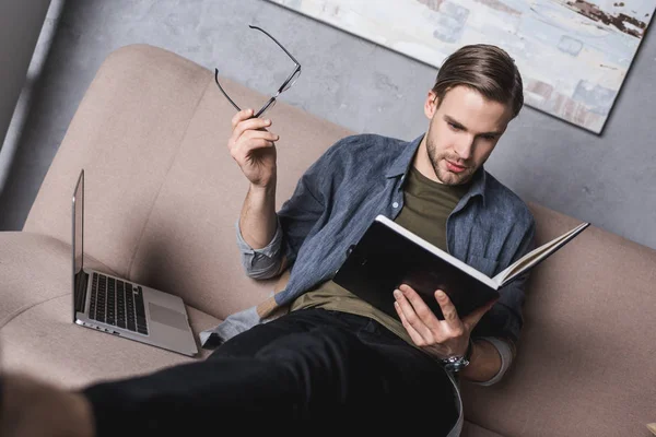 Молодий серйозний бізнесмен читає нотатки на дивані — стокове фото