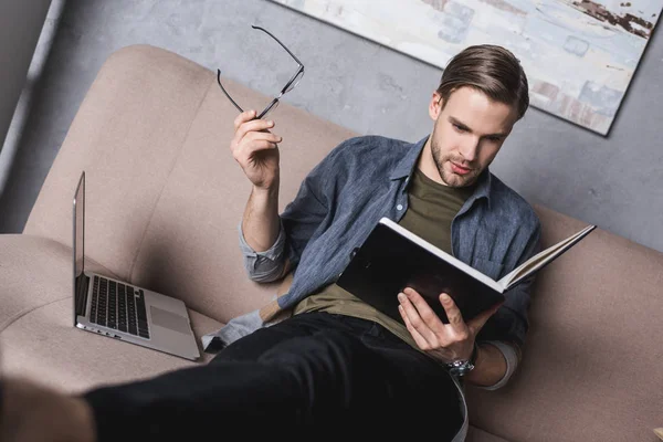 Jeune homme d'affaires sérieux lire des notes sur le canapé — Photo de stock