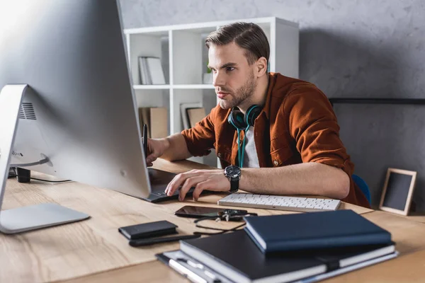 Schöner junger Mann arbeitet mit Computer im modernen Büro — Stockfoto