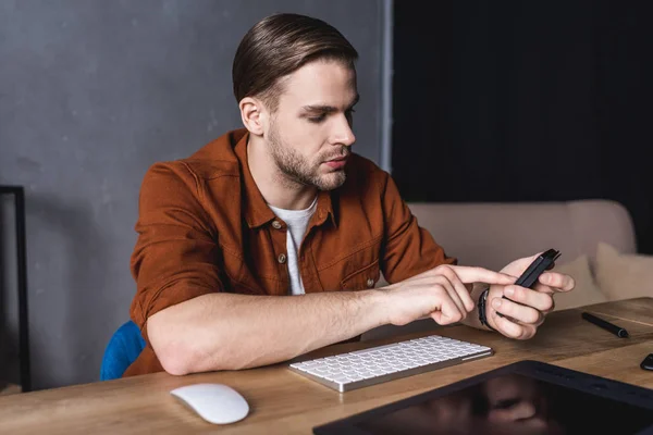 Young handsome designer using calculator at workplace — Stock Photo